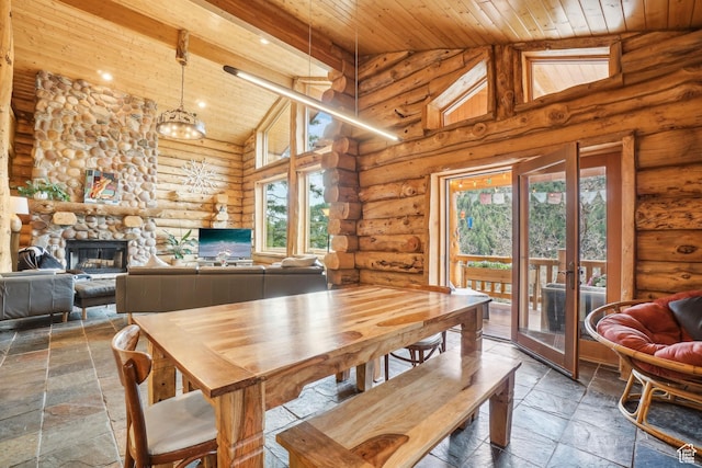dining room with high vaulted ceiling, stone tile floors, wooden ceiling, and rustic walls