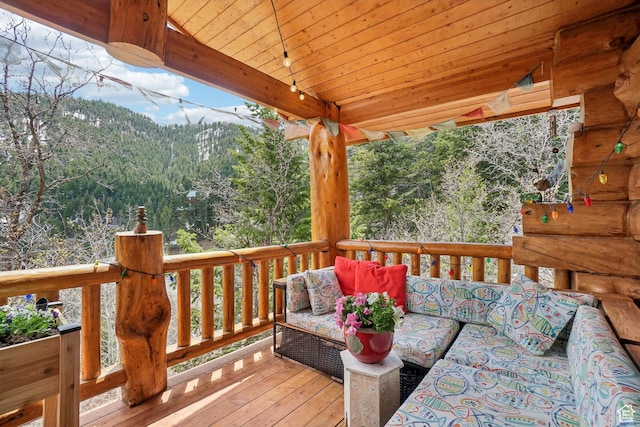 wooden terrace featuring a mountain view, outdoor lounge area, and a forest view
