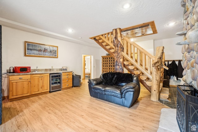 living room featuring indoor wet bar, recessed lighting, stairway, light wood-style flooring, and beverage cooler