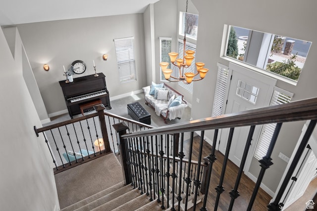 stairs featuring an inviting chandelier, a wealth of natural light, baseboards, and a high ceiling