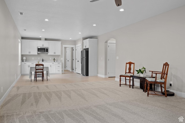 sitting room featuring a ceiling fan, recessed lighting, baseboards, arched walkways, and light colored carpet