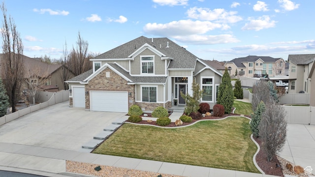 view of front of house featuring fence, stone siding, driveway, a garage, and a front yard