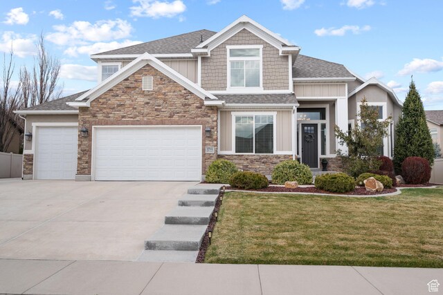 craftsman house with an attached garage, stone siding, concrete driveway, a front yard, and board and batten siding