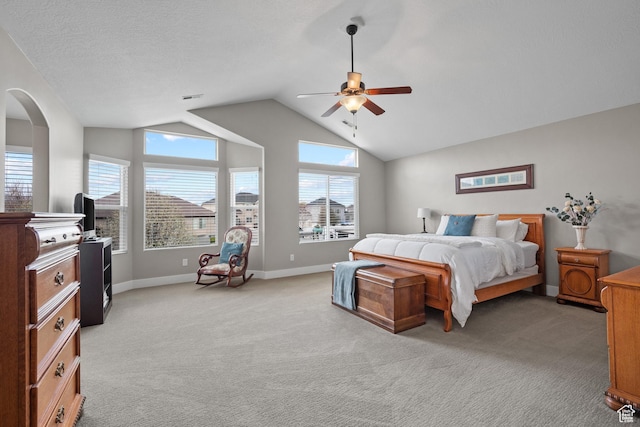 bedroom featuring lofted ceiling, ceiling fan, light carpet, arched walkways, and baseboards