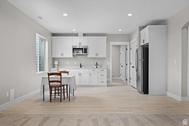 kitchen featuring light countertops, white cabinetry, stainless steel appliances, and baseboards