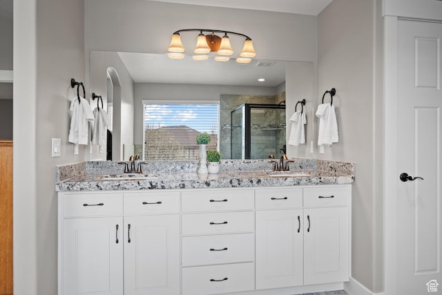 bathroom with a sink, double vanity, a stall shower, and visible vents