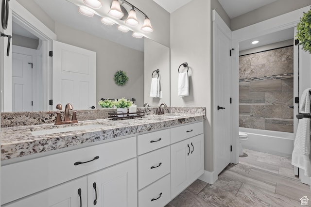 bathroom with a sink, double vanity, toilet, and bathtub / shower combination