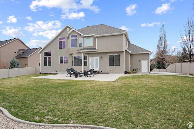 rear view of property featuring a lawn, a patio, stucco siding, and a fenced backyard