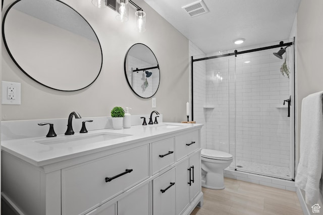 full bath featuring a sink, double vanity, toilet, and a shower stall
