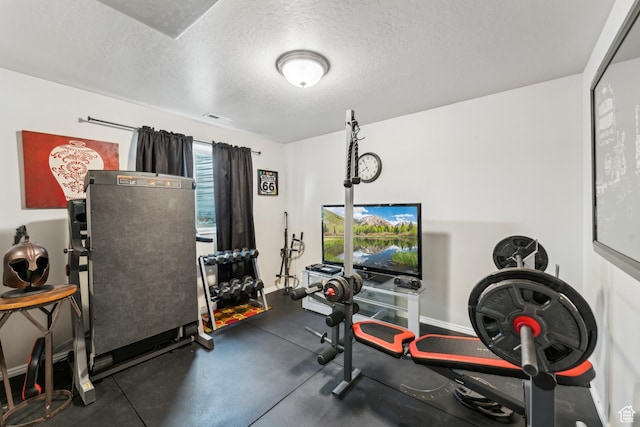 workout room with a textured ceiling, visible vents, and baseboards