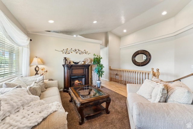 living area featuring vaulted ceiling, wood finished floors, a glass covered fireplace, and recessed lighting