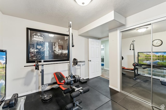 exercise room featuring a textured ceiling and baseboards