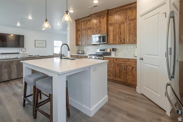 5740 Cardinal Wing Dr Unit 17, St George, UT 84790 - kitchen featuring a sink, stainless steel appliances, brown cabinets, open floor plan, and a kitchen bar