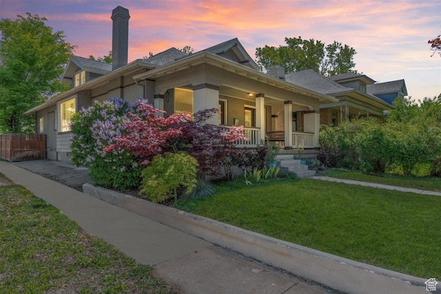view of front of property featuring a chimney, a porch, a front lawn, and fence