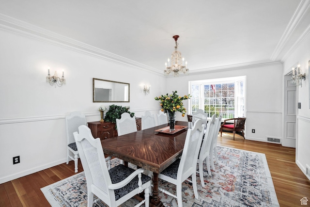 341 E E Blvd, Logan, UT 84321 - dining space featuring wood finished floors, ornamental molding, baseboards, visible vents, and a notable chandelier