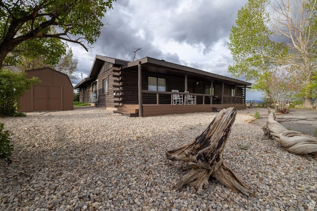 view of front of house with log siding, a storage shed, an outbuilding, and a porch