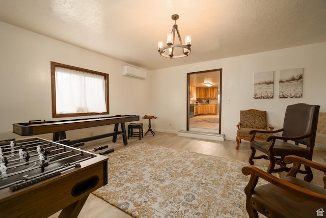 rec room featuring a wall mounted AC, a chandelier, light wood-style flooring, and baseboards