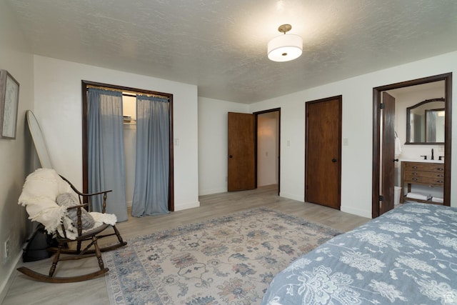 bedroom with wood finished floors, baseboards, and a textured ceiling