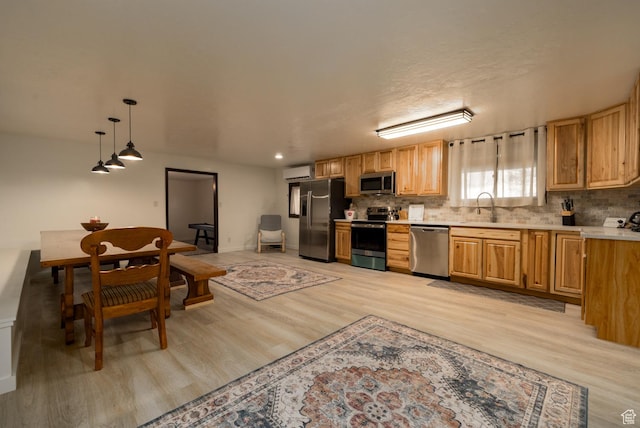 kitchen with stainless steel appliances, an AC wall unit, light wood-style flooring, light countertops, and tasteful backsplash