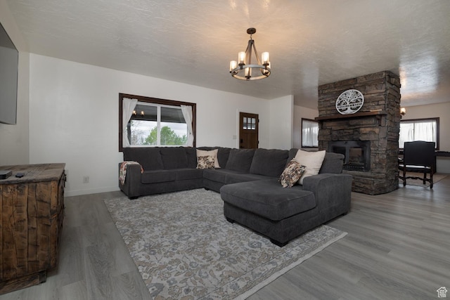 living room featuring wood finished floors, a chandelier, a fireplace, and baseboards