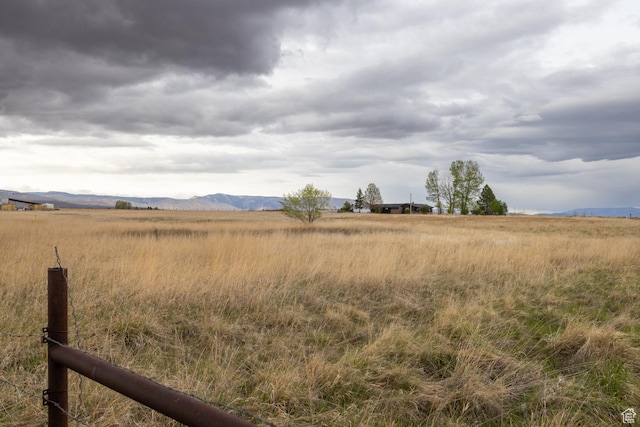 view of yard featuring a view of rural / pastoral area, a mountain view, and fence