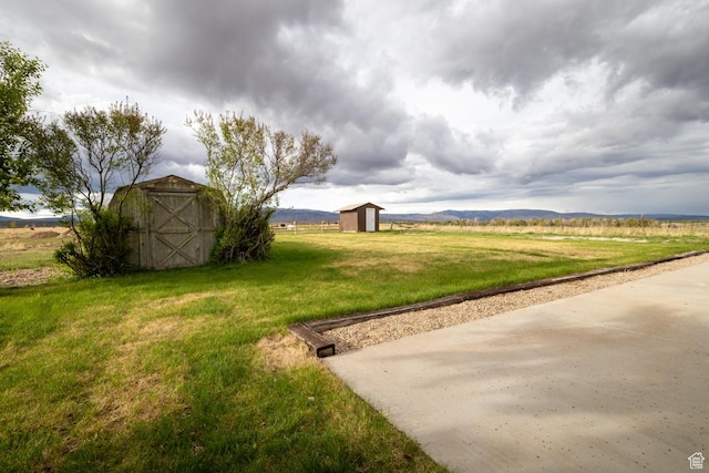 view of grassy yard with a storage unit, an outbuilding, and a view of countryside