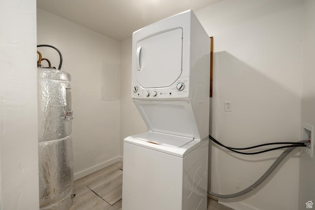 laundry area with stacked washer / dryer, light wood-type flooring, water heater, and baseboards
