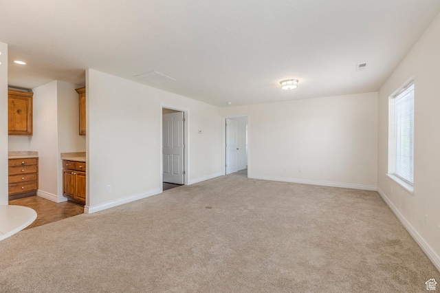 unfurnished living room with light carpet, baseboards, and visible vents