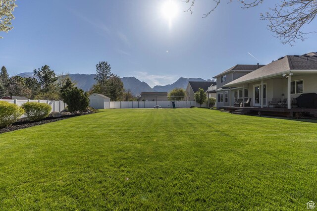 view of yard with a mountain view, an outbuilding, a fenced backyard, and a shed