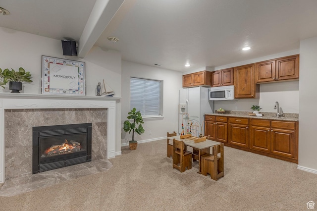 kitchen featuring recessed lighting, brown cabinetry, white appliances, a tiled fireplace, and light colored carpet