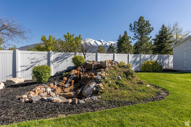 view of yard featuring a fenced backyard, a storage shed, a mountain view, and an outbuilding
