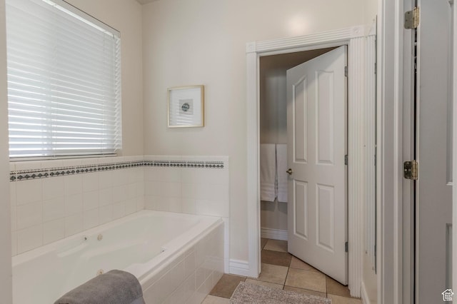 bathroom with tile patterned flooring, baseboards, and a bath