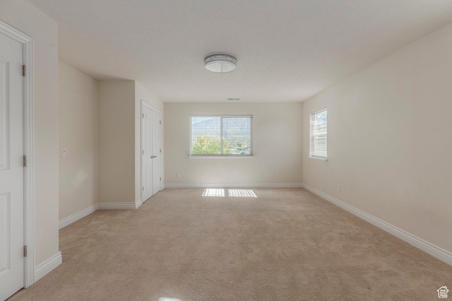 unfurnished room with light carpet and baseboards