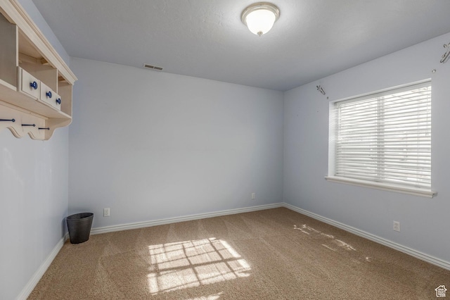 carpeted spare room featuring baseboards and visible vents