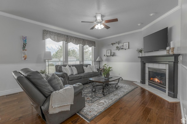 living room with a ceiling fan, ornamental molding, a fireplace, and visible vents