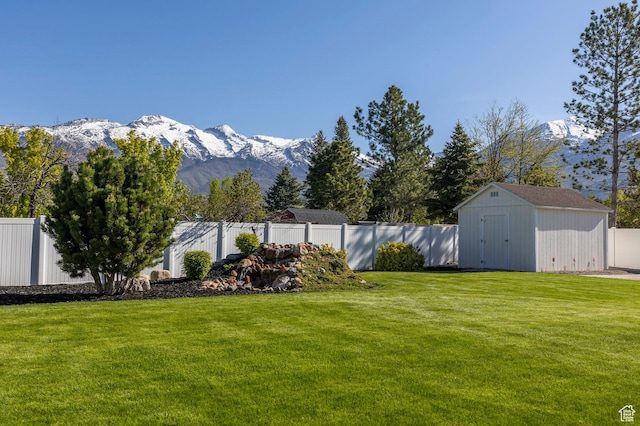 view of yard with a storage unit, an outdoor structure, a fenced backyard, and a mountain view