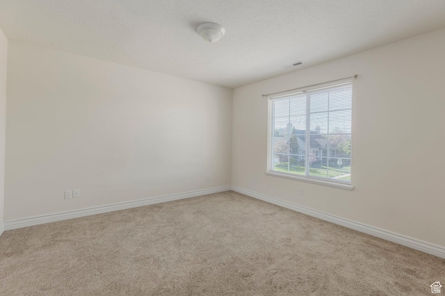 carpeted spare room featuring baseboards and visible vents