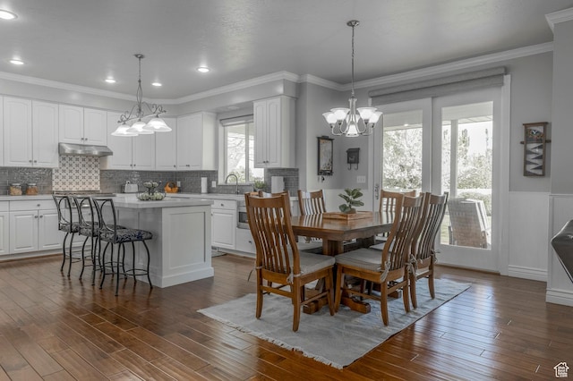 dining area with ornamental molding, recessed lighting, a chandelier, dark wood-style flooring, and wainscoting