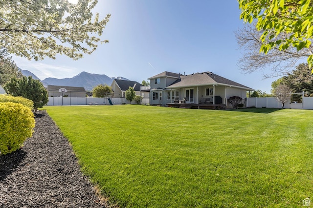 view of yard featuring a deck with mountain view and a fenced backyard