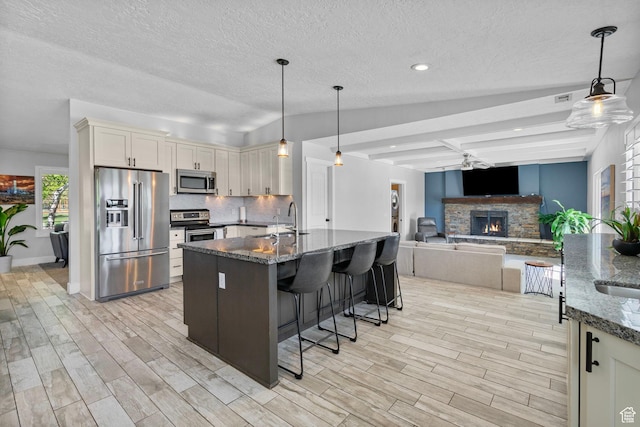 11549 S Equestrian Dr W, South Jordan, UT 84095 - kitchen with a sink, dark stone counters, light wood-style floors, stainless steel appliances, and tasteful backsplash