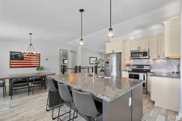 11549 S Equestrian Dr W, South Jordan, UT 84095 - kitchen with a textured ceiling, light wood finished floors, an inviting chandelier, a sink, and stainless steel appliances