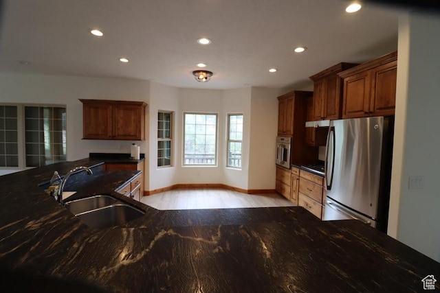 kitchen with recessed lighting, baseboards, a sink, light wood-style floors, and stainless steel appliances