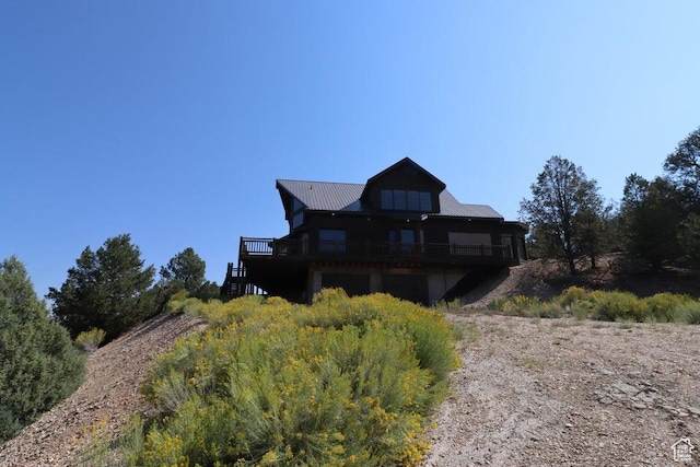 rear view of house featuring metal roof, stairway, and a wooden deck