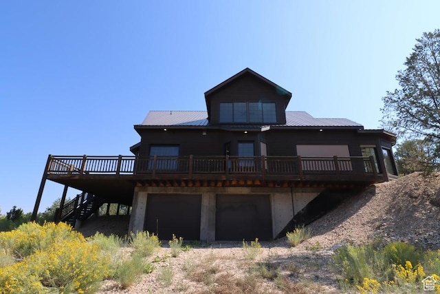 rear view of house featuring metal roof, a garage, stairway, and a wooden deck