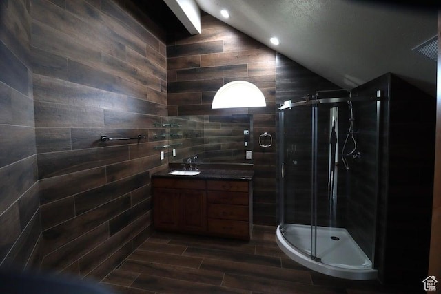 bathroom featuring vanity, vaulted ceiling, wood finished floors, and a shower stall