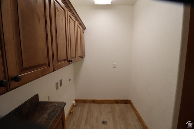 laundry room with baseboards, light wood finished floors, and cabinet space