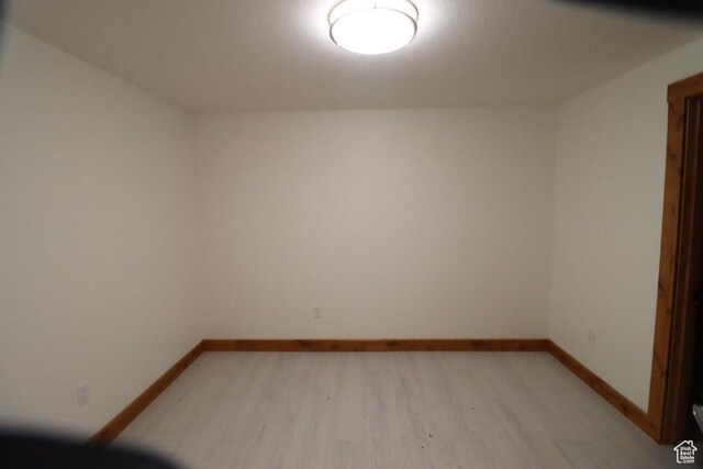empty room featuring baseboards and light wood finished floors