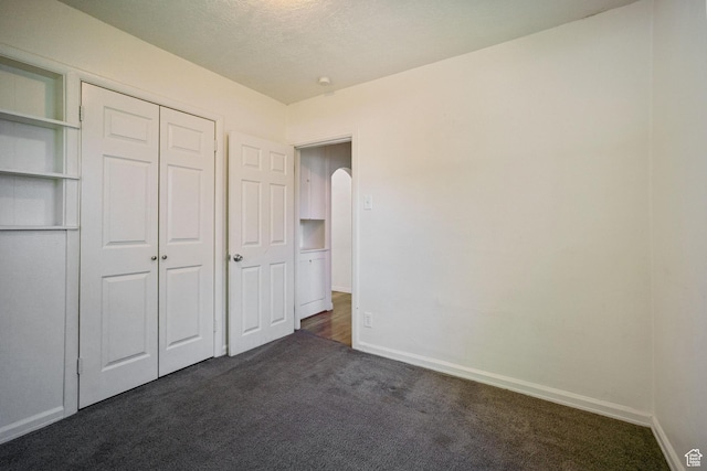 370 E Scott Ave, South Salt Lake, UT 84115 - unfurnished bedroom featuring dark colored carpet, baseboards, arched walkways, and a closet