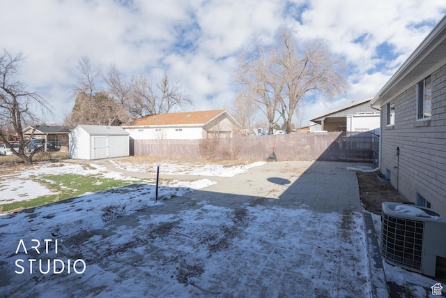 yard layered in snow with a residential view, a storage unit, cooling unit, a fenced backyard, and an outbuilding