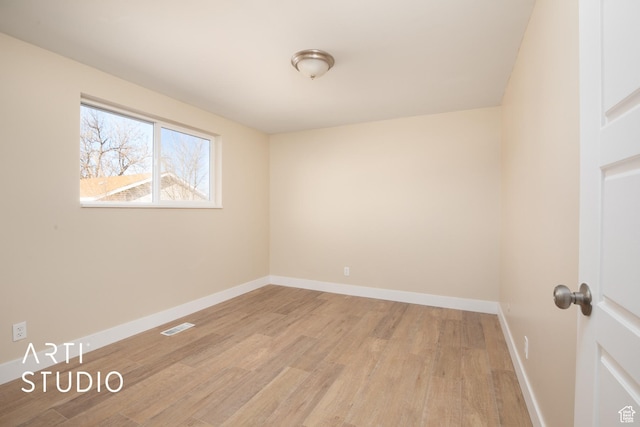 unfurnished room with light wood finished floors, visible vents, and baseboards